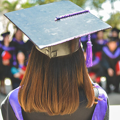 female with cap and gown looking at class