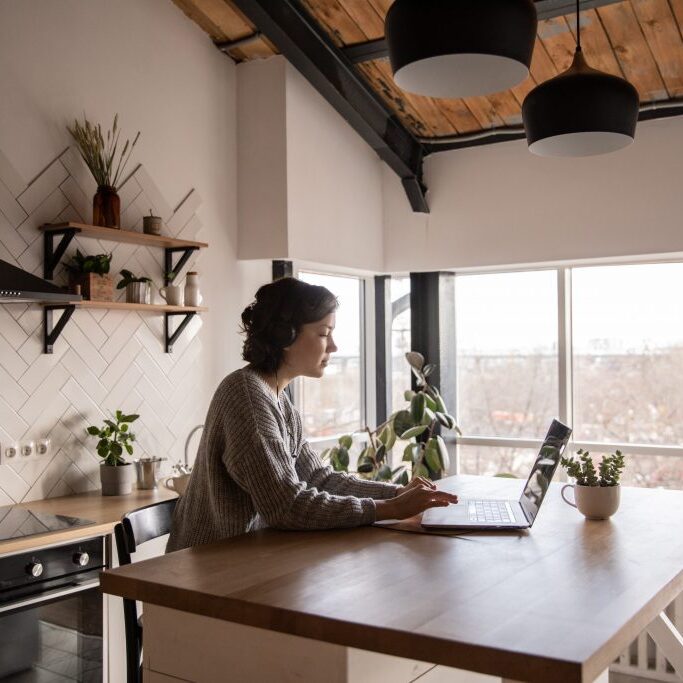 woman looking at laptop in her kitchen